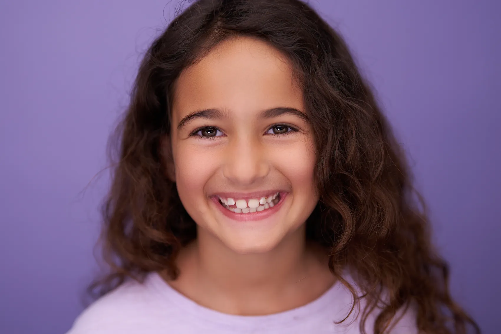 Girl laughing on a soft lilac backdrop